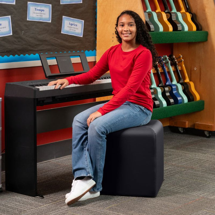 Jaxx Monroe 18in foam ottoman in black vinyl, used as classroom seating in a music room