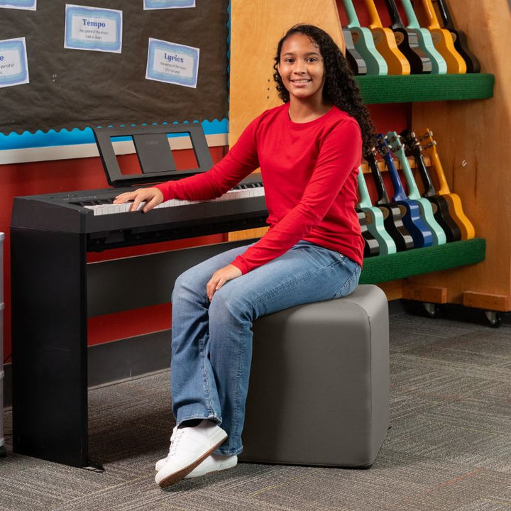Jaxx Monroe 18in foam ottoman in grey vinyl, used as classroom seating in a music room