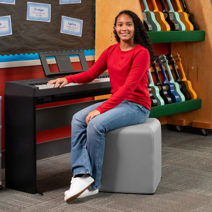 Jaxx Monroe 18in foam ottoman in light grey vinyl, used as classroom seating in a music room