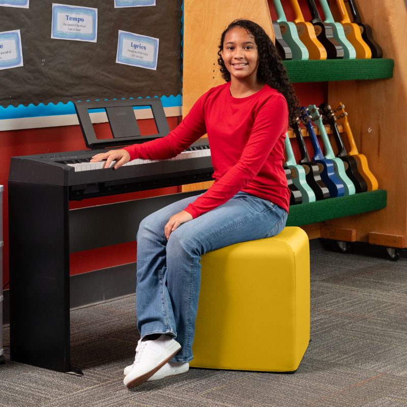 Jaxx Monroe 18in foam ottoman in yellow vinyl, used as classroom seating in a music room