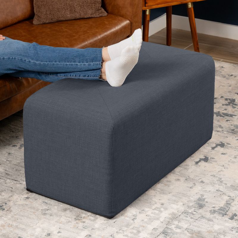 Jaxx Monroe 36in rectangular foam ottoman in denim performance fabric, used as a footrest in a living room setting