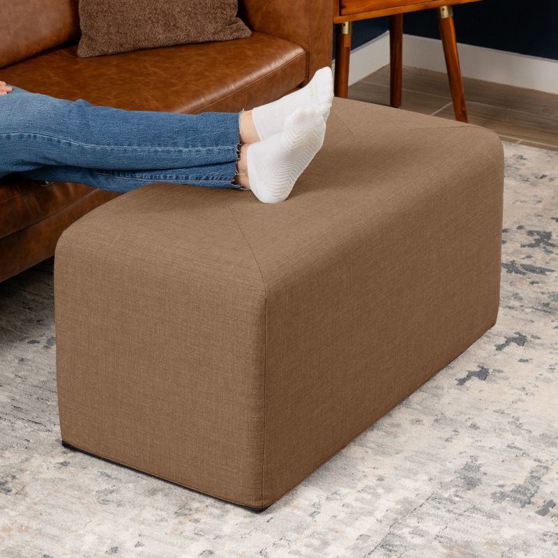 Jaxx Monroe 36in rectangular foam ottoman in earth brown performance fabric, used as a footrest in a living room setting