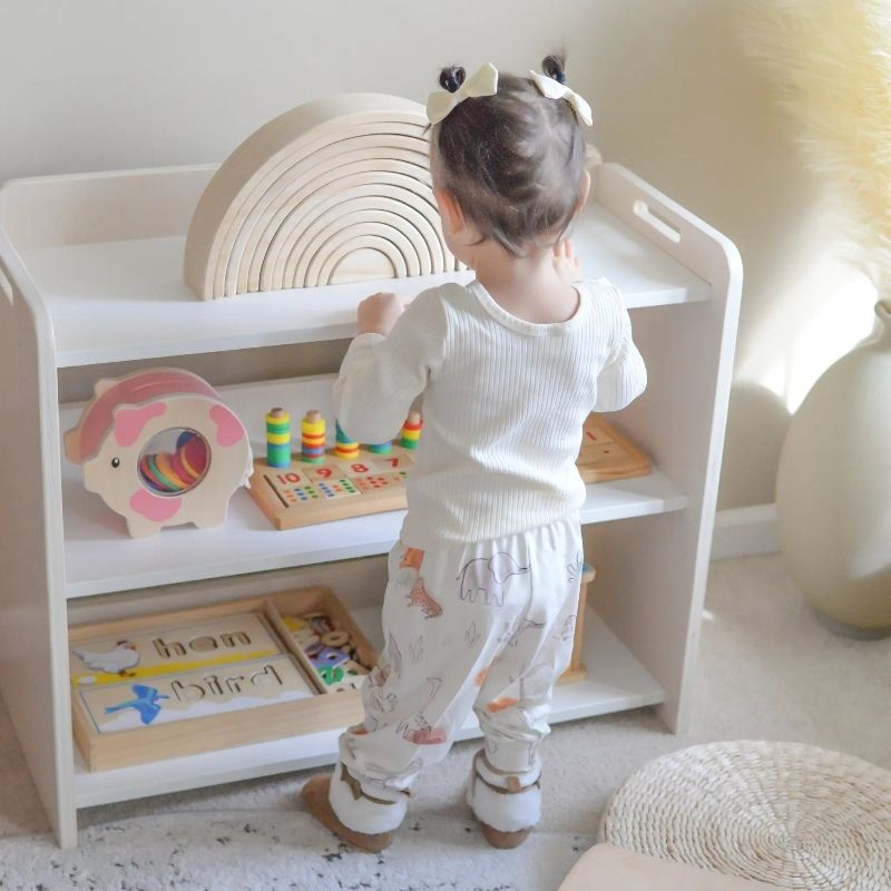 Child independently accessing materials from the Sapiens Child Banana Montessori Shelf with Borders, showing the child-sized open-access design and raised top borders for toddlers aged 12 months to 5 years