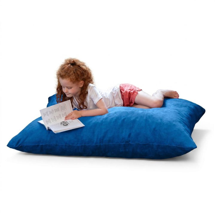 Young reader stretched out on a Blueberry microsuede Jaxx Pillow Saxx 4 kids floor pillow, soft bean bag floor seating for storytime