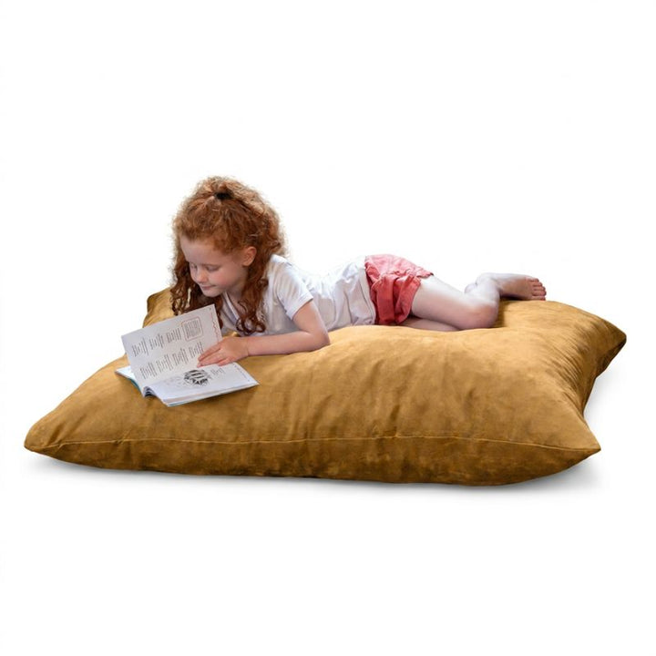 Child lying on a Jaxx Pillow Saxx 4 bean bag floor pillow in Camel microsuede, enjoying a book on a washable kids floor cushion