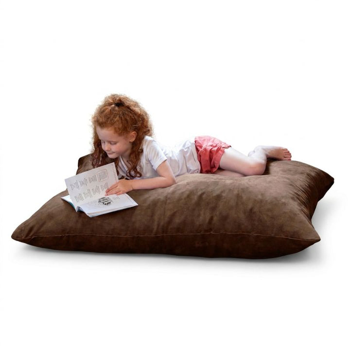 Young reader on a Chocolate microsuede Jaxx Pillow Saxx 4 kids floor pillow, a warm-toned bean bag floor cushion for quiet time