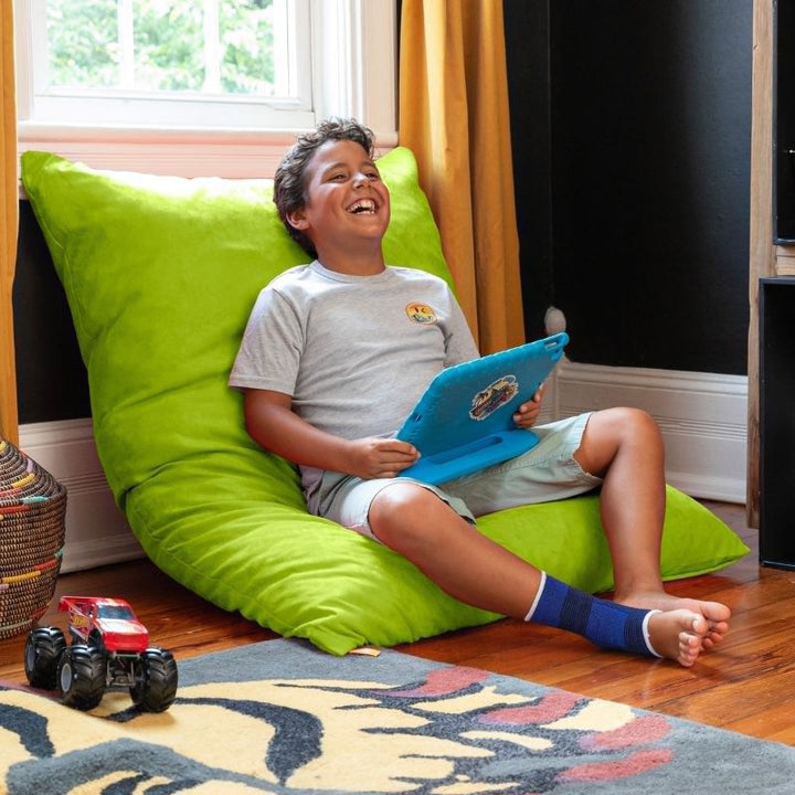 Boy relaxing against a Lime Jaxx Pillow Saxx 4 bean bag floor pillow, a cheerful kids floor cushion set upright in a playroom