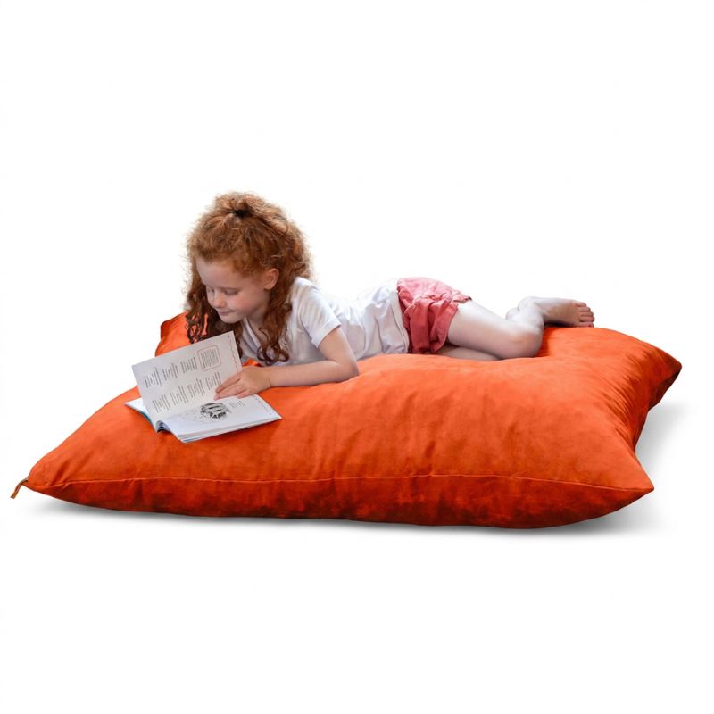 Young reader lying on a Mandarin microsuede Jaxx Pillow Saxx 4 kids floor pillow, a vibrant bean bag floor cushion for reading nooks