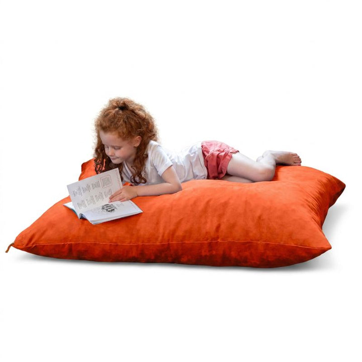 Young reader lying on a Mandarin microsuede Jaxx Pillow Saxx 4 kids floor pillow, a vibrant bean bag floor cushion for reading nooks