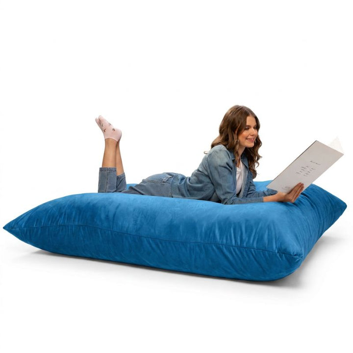 Adult relaxing with a book on a Blueberry Jaxx Pillow Saxx 5 bean bag floor pillow, a giant crash pillow for reading and rest