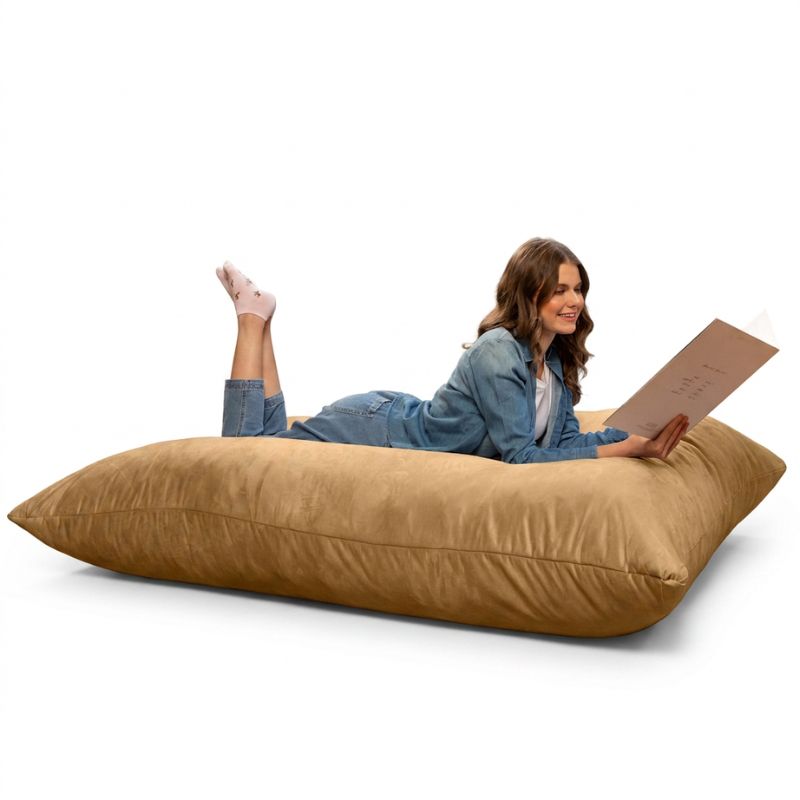 Woman lying on a Jaxx Pillow Saxx 5 giant bean bag floor pillow in Camel, a warm neutral floor cushion for family rooms