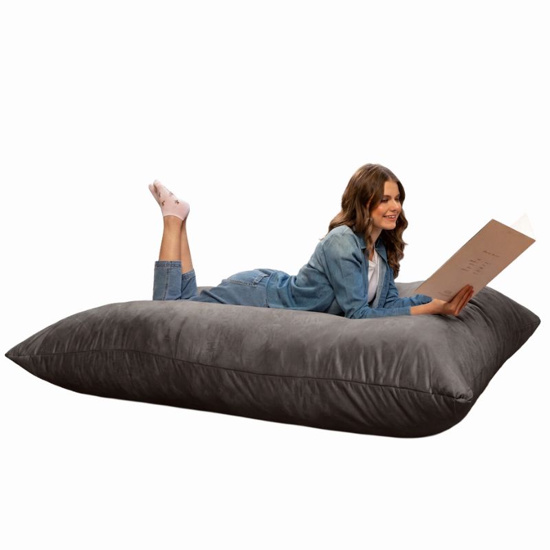 Reader stretched out on a Charcoal Jaxx Pillow Saxx 5 bean bag floor pillow, a giant floor cushion for calm corners