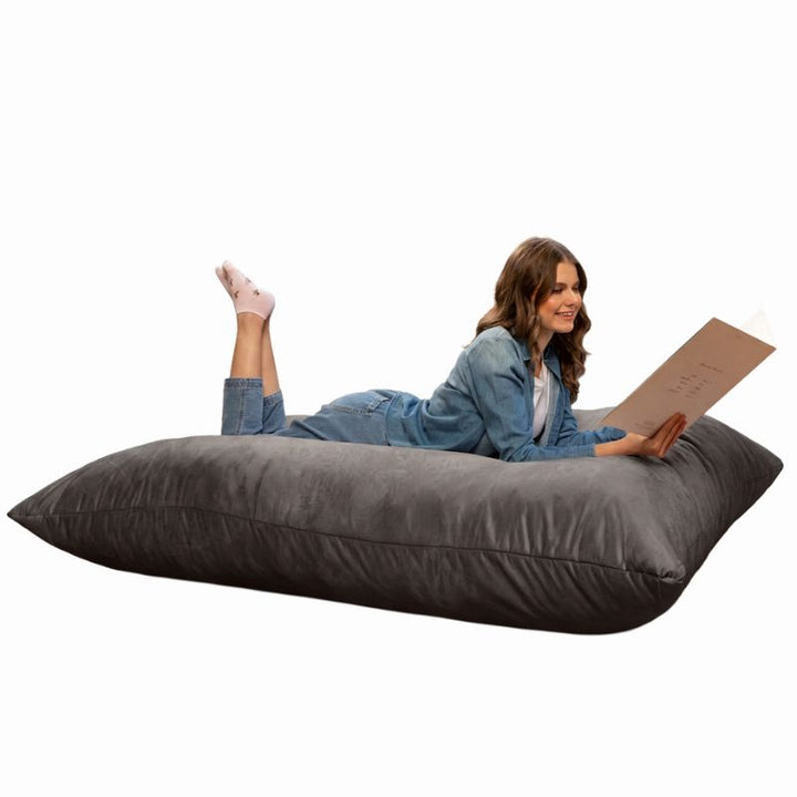 Reader stretched out on a Charcoal Jaxx Pillow Saxx 5 bean bag floor pillow, a giant floor cushion for calm corners