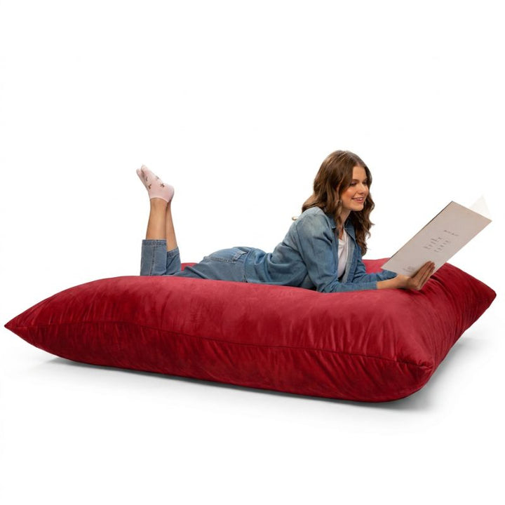 Adult reading on a Cinnabar Jaxx Pillow Saxx 5 bean bag floor pillow, a bold giant floor cushion for living rooms