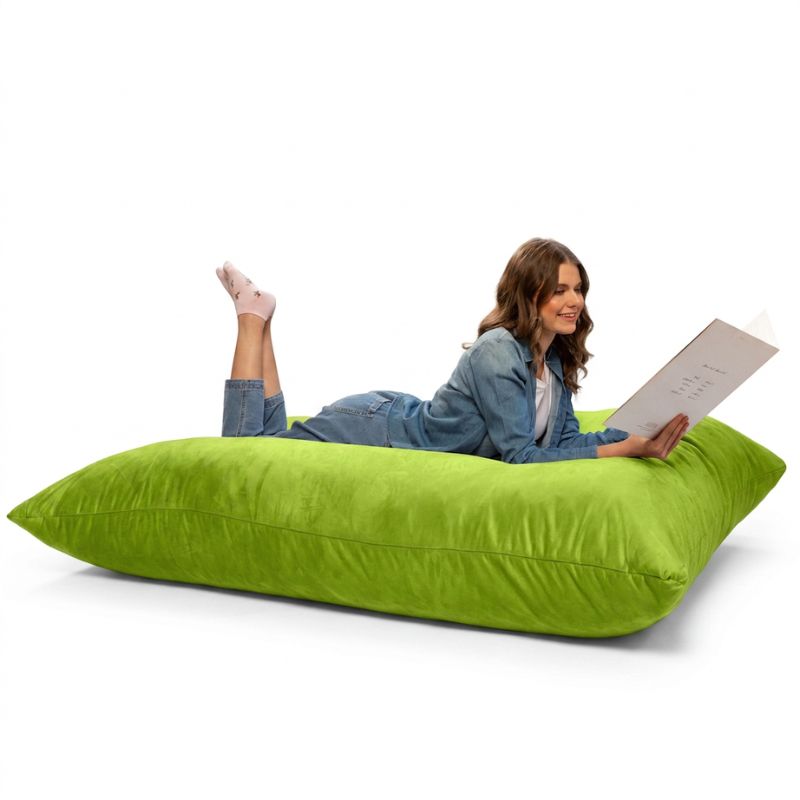 Woman lounging with a book on a Jaxx Pillow Saxx 5 giant bean bag floor pillow in Lime, a bright oversized floor cushion