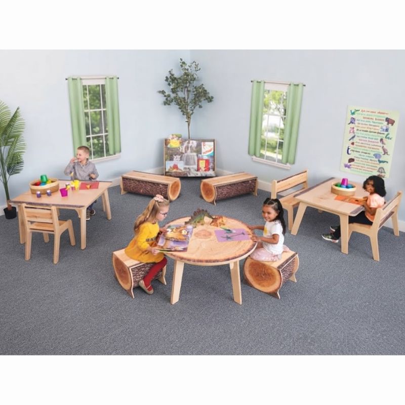 Children reading and playing with dinosaur toys around a Whitney Brothers Nature View Live Edge Round Table on log stools in a biophilic classroom