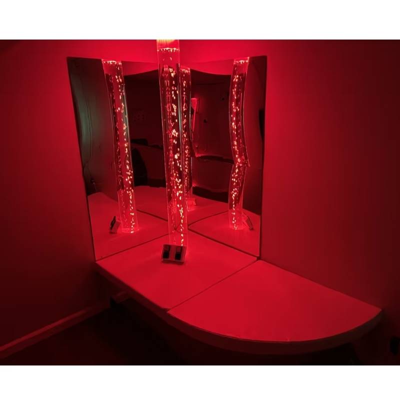 TFH Calm Bubble Corner Kit installed in a mirrored sensory room corner, glowing red for calming visual stimulation