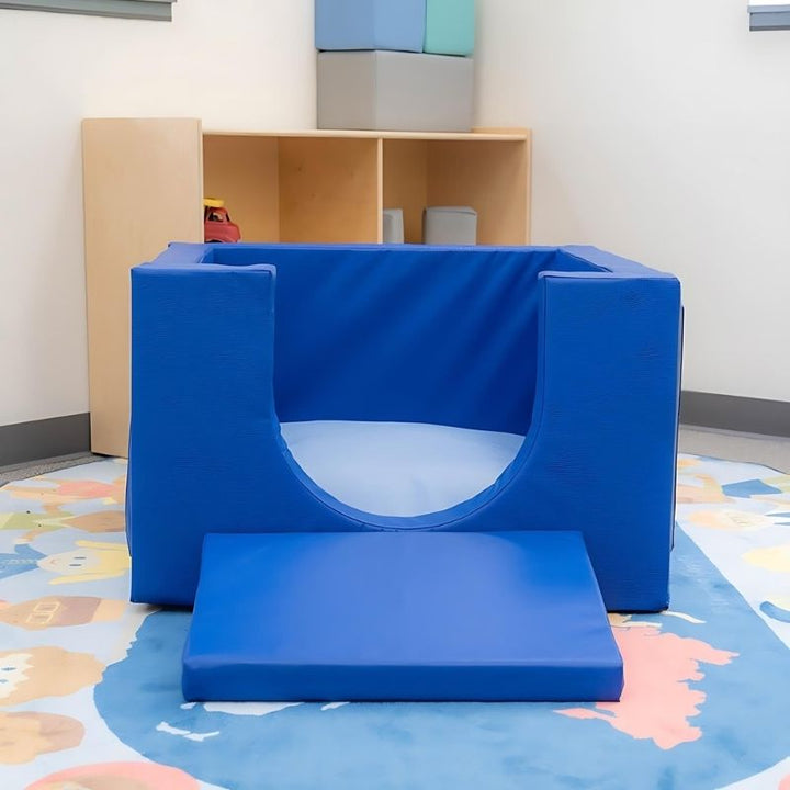 Children's Factory Cozy Cube shown indoors in a classroom or nursery setting, demonstrating the soft foam crawl-in play enclosure for infants and toddlers from 8 months