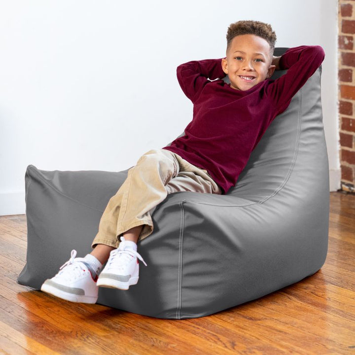 Child leaning back on the Jaxx Pezzi classroom bean bag chair in charcoal vinyl, supportive flexible seating