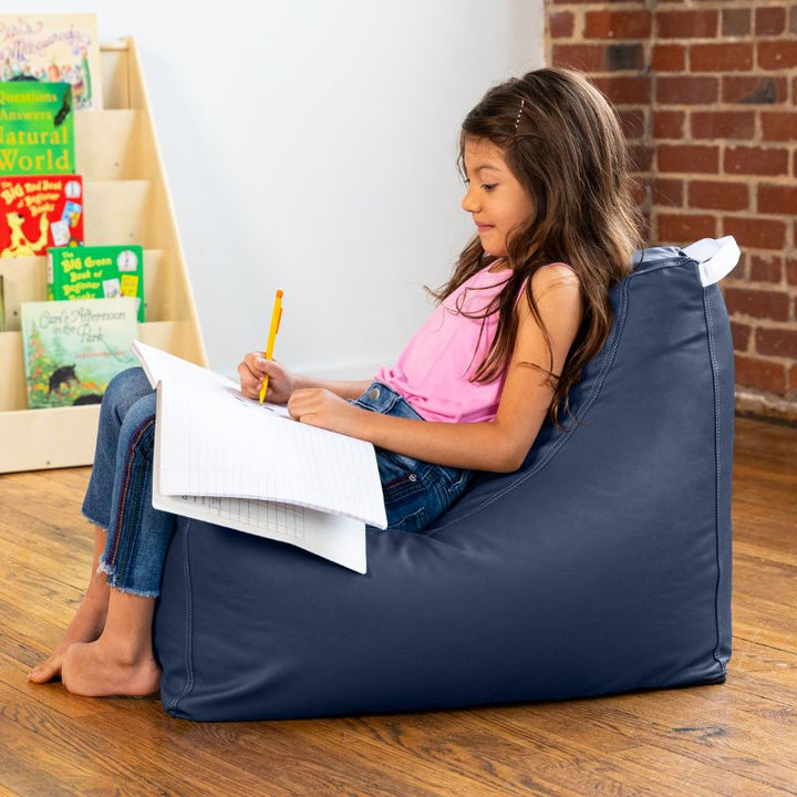 Child doing schoolwork on the Jaxx Pezzi classroom bean bag chair in navy blue vinyl in a school reading nook