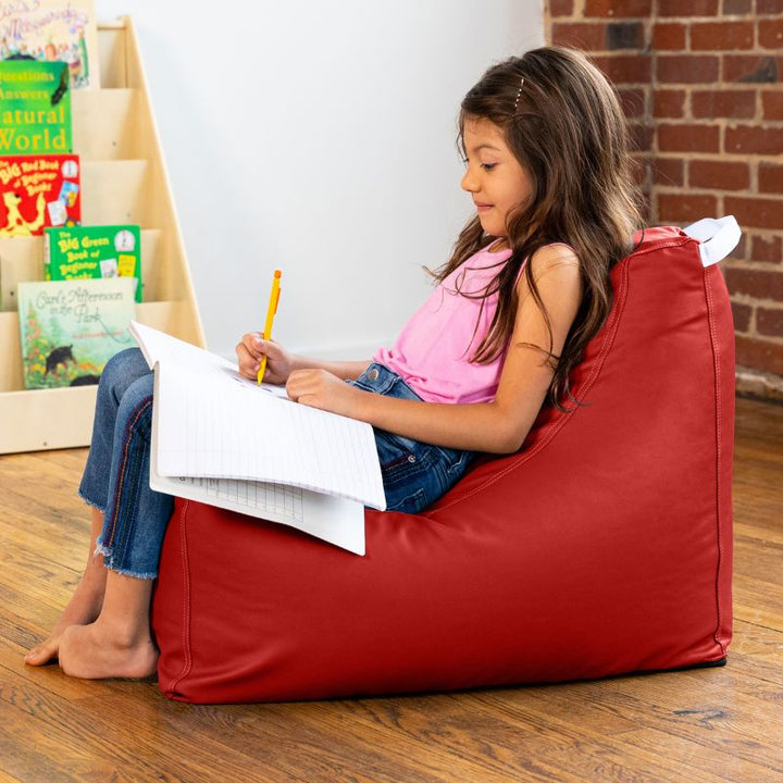 Child doing schoolwork on the Jaxx Pezzi classroom bean bag chair in red vinyl, supportive seating for independent work