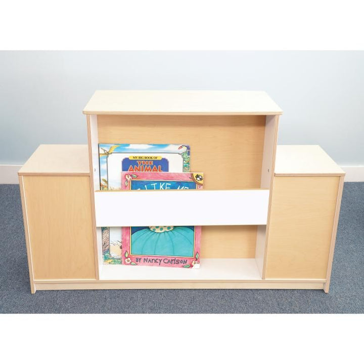 Back of the Whitney Brothers Warm and Welcoming Fireplace with oversized picture books in its storage ledge, a classroom fireplace that doubles as a library display