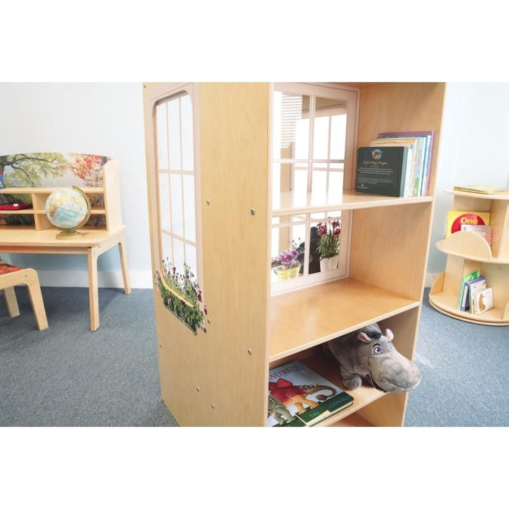 Rear bookshelf of the Whitney Brothers Nature View Window Seat holding picture books and a plush toy, set up as a classroom reading nook beside other Nature View furniture