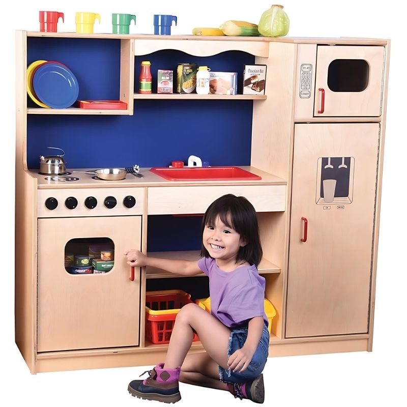 Child actively playing at the Constructive Playthings Five-In-One Kitchen, showing all five appliances in the all-in-one dramatic play kitchen for classrooms and home
