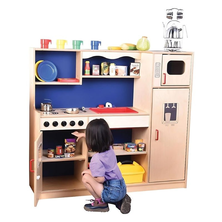Child organising play supplies at the Constructive Playthings Five-In-One Kitchen refrigerator, showing the built-in egg compartment and storage detail of this all-in-one classroom play kitchen