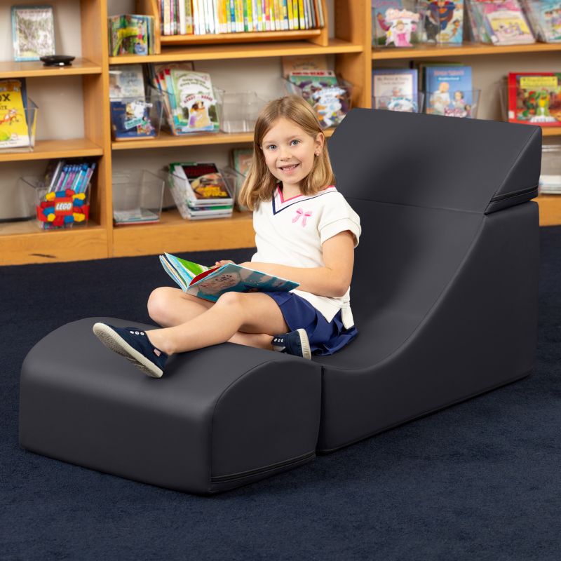 A child reading while seated in the Jaxx Flexx convertible foam chair in black vinyl, flexible seating for classrooms and calm corners