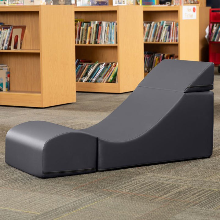 Jaxx Flexx convertible foam chair in charcoal vinyl staged in a school library reading corner