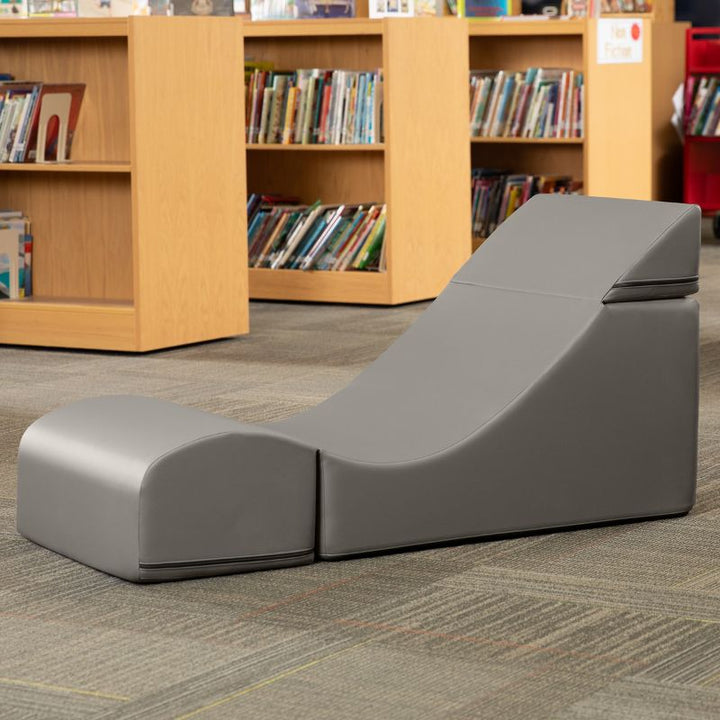 Jaxx Flexx convertible foam chair in grey vinyl staged in a school library reading corner