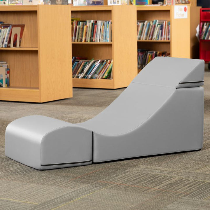 Jaxx Flexx convertible foam chair in grey vinyl staged in a school library reading corner
