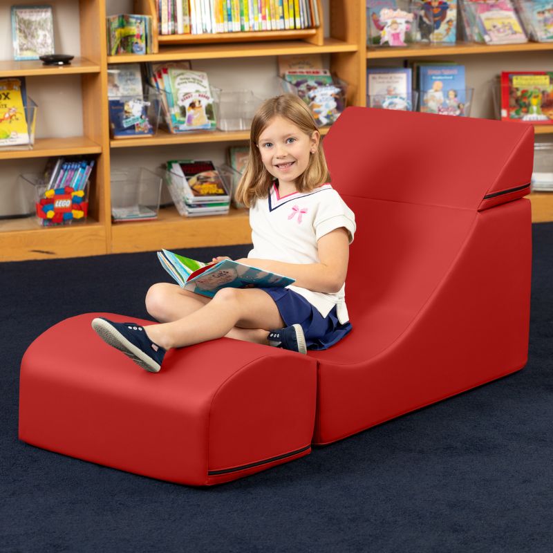 A child reading while seated in the Jaxx Flexx convertible foam chair in red vinyl, flexible seating for school libraries and calm corners
