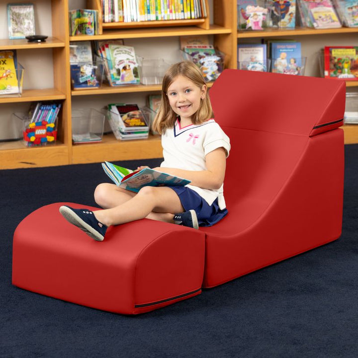 A child reading while seated in the Jaxx Flexx convertible foam chair in red vinyl, flexible seating for school libraries and calm corners