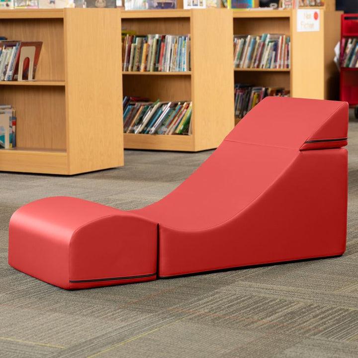 Jaxx Flexx convertible foam chair in red vinyl staged in a school library reading corner