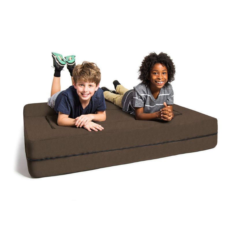 Two kids on the Jaxx Zipline flip sofa in brown, demonstrating the flattened bed position at true scale