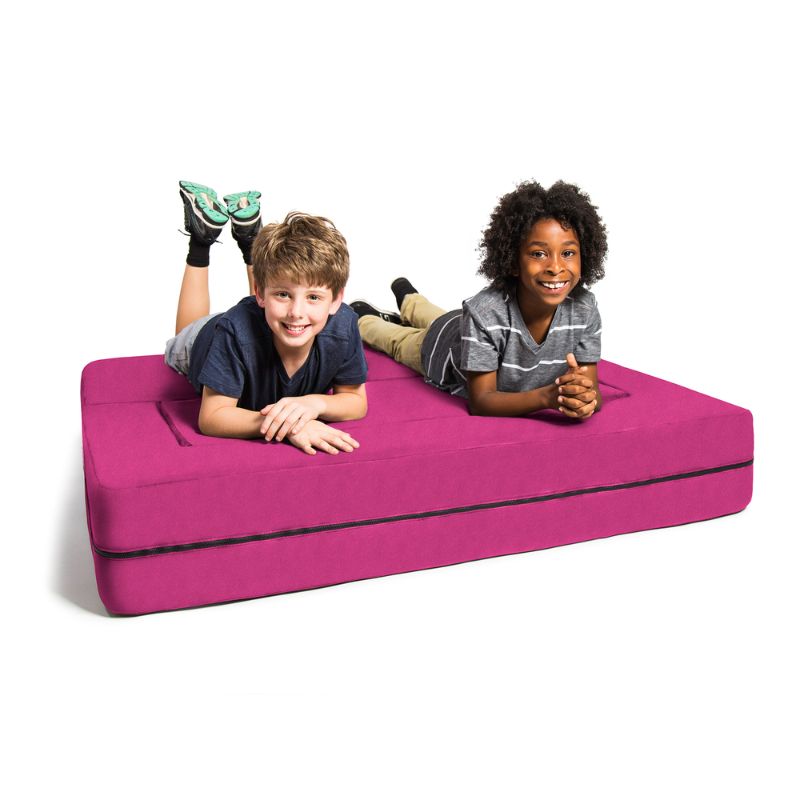 Two kids lying on the Jaxx Zipline convertible kids sofa in pink, unfolded flat into its lounging bed configuration