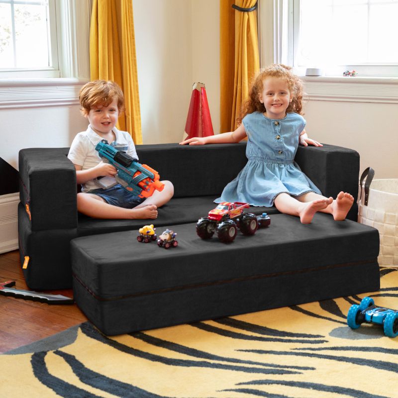 Two kids playing with toys on the Jaxx Zipline convertible kids sofa and ottoman in black