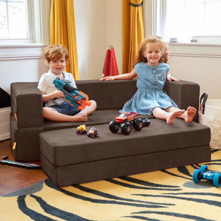 Two kids playing on the Jaxx Zipline convertible kids sofa and ottoman in brown