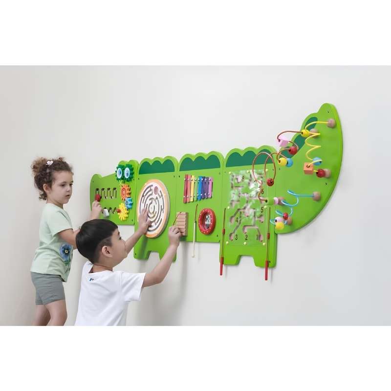 Two children playing with the TFH Crocodile Activity Wall Panel mounted on a wall, exploring gears, mazes and a xylophone on this sensory wall panel
