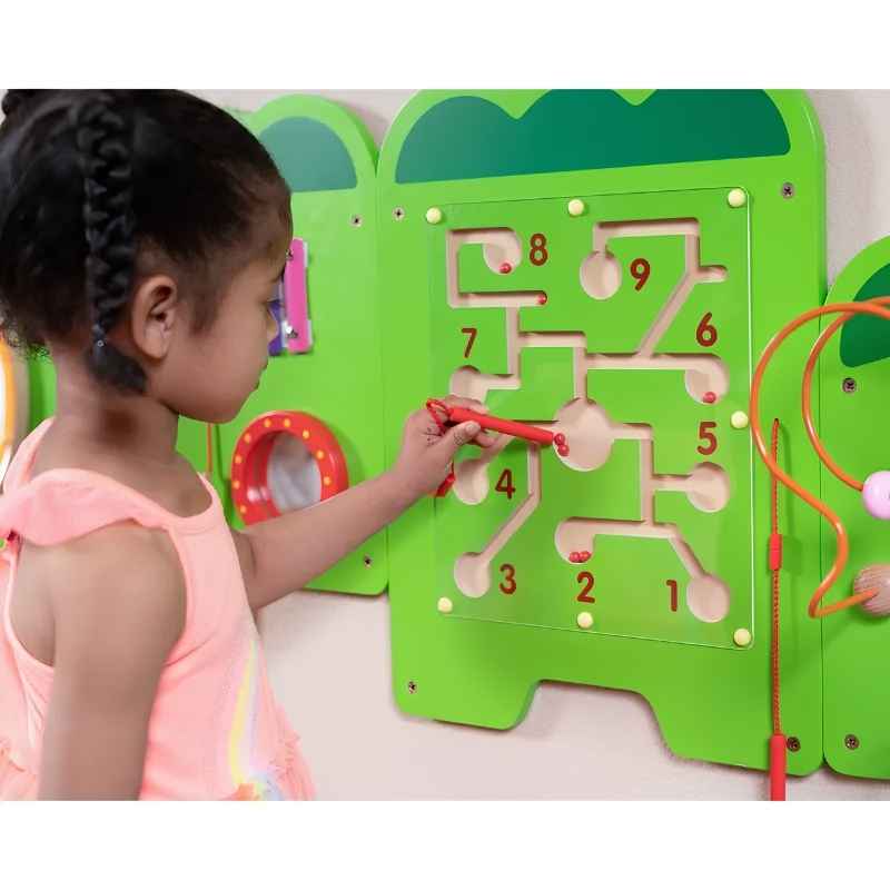 A child traces beads along the numbered maze panel of the TFH Crocodile Activity Wall Panel, a sensory wall panel activity for group play