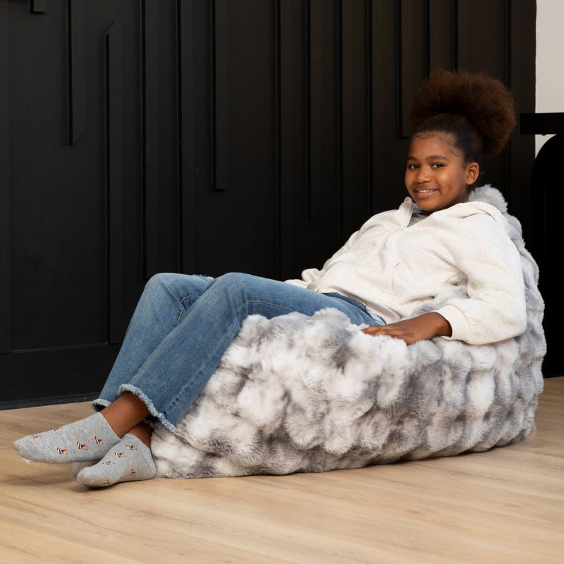 Girl reclining on the CrashPuff by Raven-Symoné sensory floor lounger propped upright in Phantom Gray