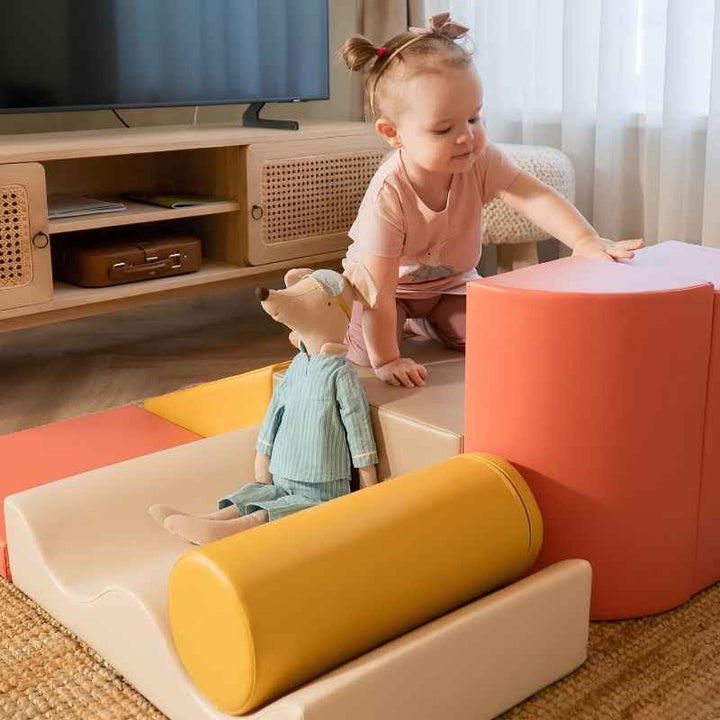 Toddler reaching for a foam piece of the IGLU Discoverer Soft Play Set in Pastel Fries beside a stuffed toy