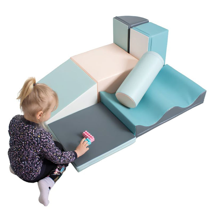 Girl playing with building blocks beside the IGLU Discoverer Soft Play Set in Pastel Turquoise