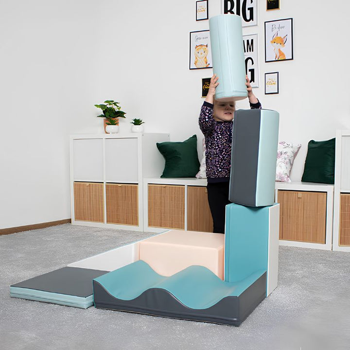Girl stacking a foam cylinder piece from the IGLU Discoverer Soft Play Set in Pastel Turquoise