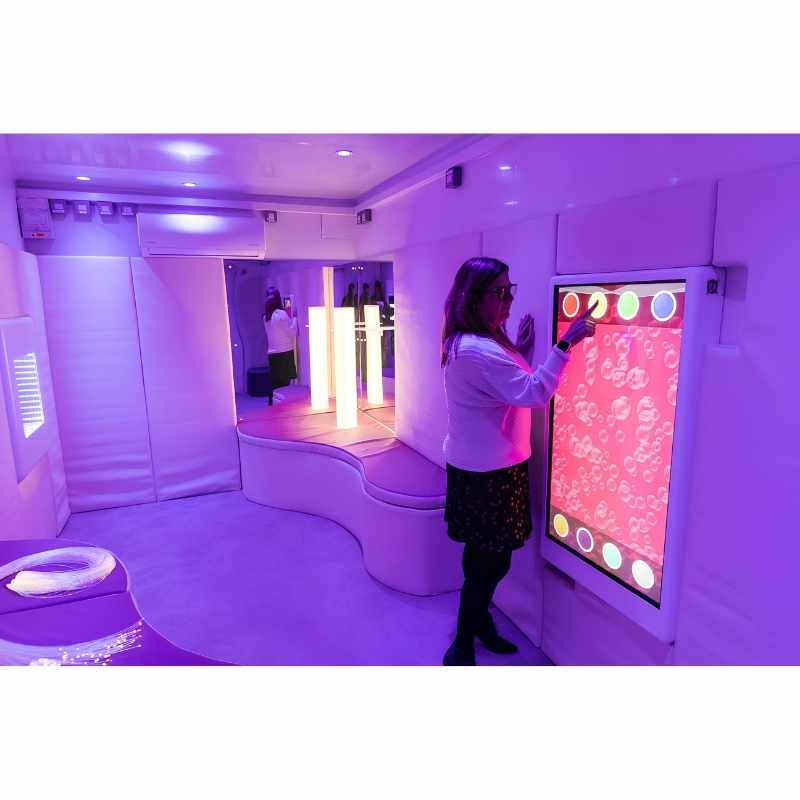 Adult engaging with the Experia Intelli Panel Bubble Wall sensory wall panel in a purple sensory room