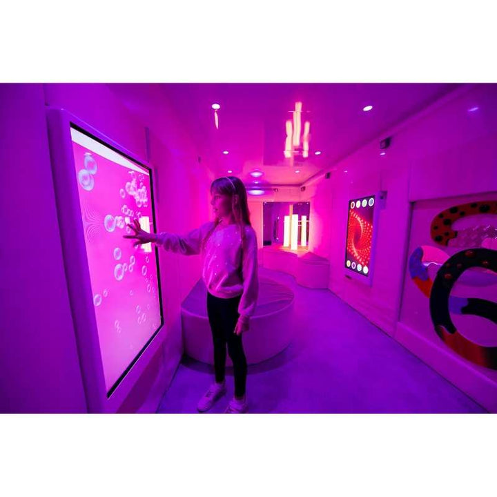 Teen engaging with the Experia Intelli Panel Bubble Wall touchscreen sensory wall panel in a pink sensory room