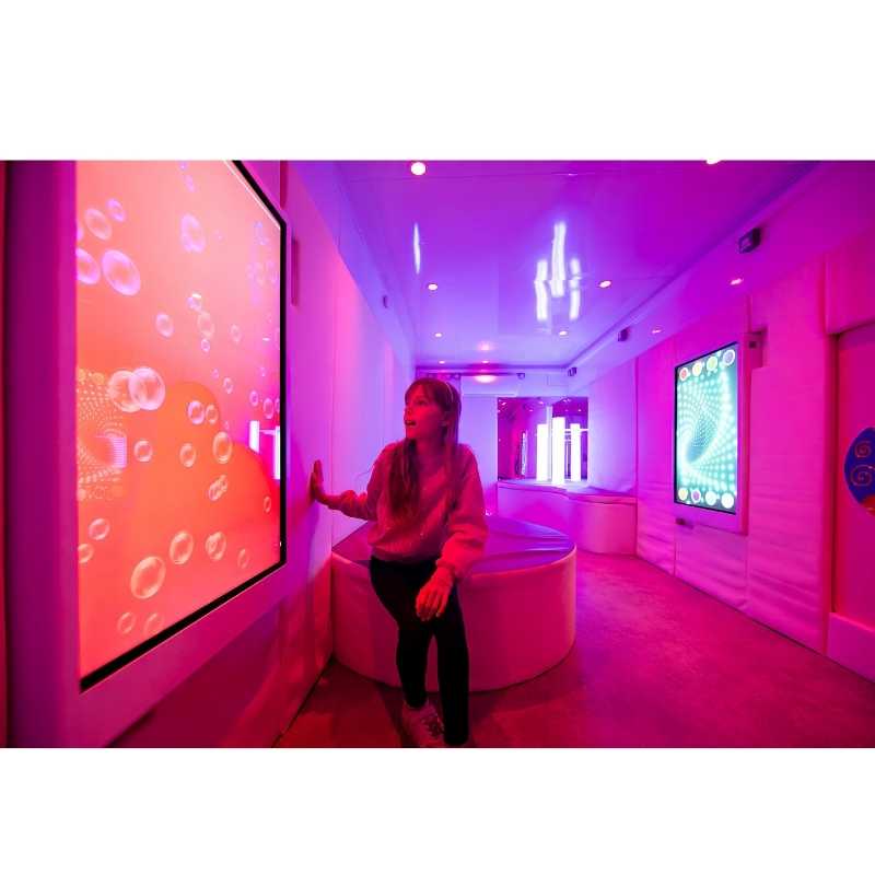 Teen seated and engaging with the Experia Intelli Panel Bubble Wall sensory wall panel in a pink sensory room