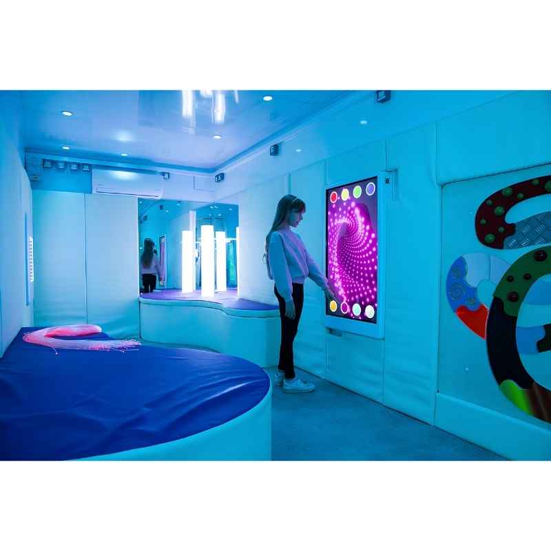 Landscape view of a teen engaging with the Experia Intelli Panel Infinity interactive sensory wall panel in a blue-lit room